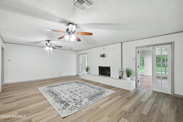 301 Estainville Ave, Lafayette, LA 70508 - unfurnished living room with ceiling fan, light wood finished floors, a textured ceiling, and a brick fireplace