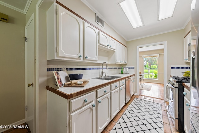 110 Shipley Dr, Lafayette, LA 70508 - kitchen with appliances with stainless steel finishes, tile countertops, backsplash, white cabinetry, and crown molding