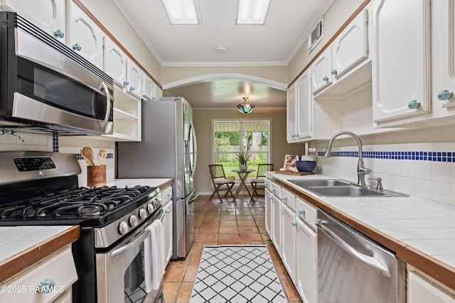 110 Shipley Dr, Lafayette, LA 70508 - kitchen with stainless steel appliances, tile counters, white cabinets, crown molding, and tasteful backsplash