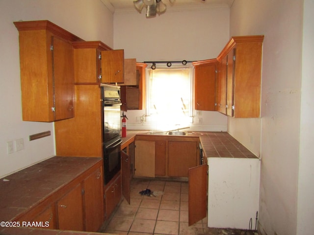120 W Saint Peter St, New Iberia, LA 70560 - kitchen with tile counters, ornamental molding, brown cabinetry, light tile patterned flooring, and ceiling fan