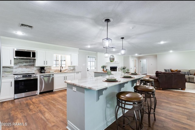 381 Rue Dauphine, Eunice, LA 70535 - kitchen featuring stainless steel appliances, open floor plan, dark wood finished floors, ornamental molding, and a center island