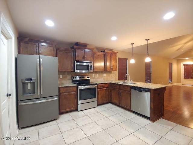 120 Acacia Ln, Abbeville, LA 70510 - kitchen with stainless steel appliances, a peninsula, light tile patterned flooring, backsplash, and decorative light fixtures