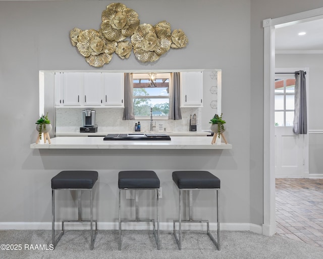809 Dartez Dr, New Iberia, LA 70563 - kitchen with white cabinetry, a peninsula, a kitchen breakfast bar, and crown molding