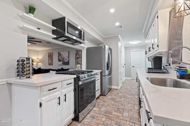 809 Dartez Dr, New Iberia, LA 70563 - kitchen with appliances with stainless steel finishes, brick flooring, crown molding, white cabinets, and a peninsula