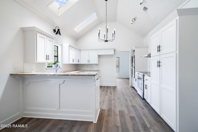 806 Beaujolais Pkwy, Lafayette, LA 70503 - kitchen featuring a skylight, a peninsula, a chandelier, stainless steel electric range oven, and healthy amount of natural light