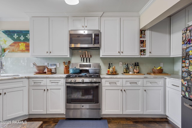 234 Ridgewood St, Lafayette, LA 70506 - kitchen featuring appliances with stainless steel finishes, ornamental molding, backsplash, white cabinets, and dark wood finished floors
