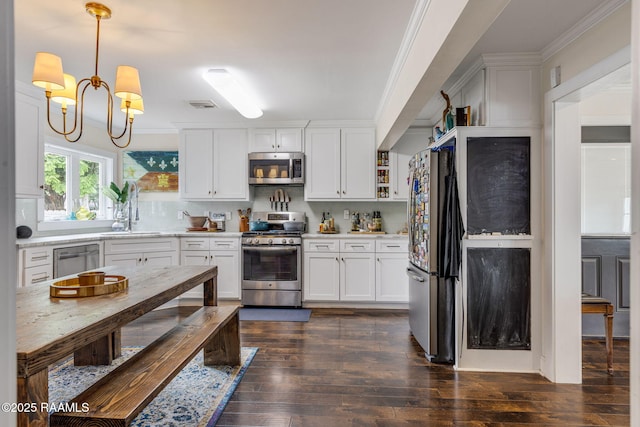 234 Ridgewood St, Lafayette, LA 70506 - kitchen featuring stainless steel appliances, light countertops, dark wood finished floors, white cabinetry, and ornamental molding