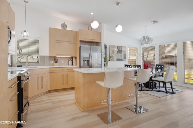 3703 Daspit Rd, New Iberia, LA 70563 - kitchen featuring stainless steel appliances, light brown cabinetry, light wood finished floors, light countertops, and pendant lighting
