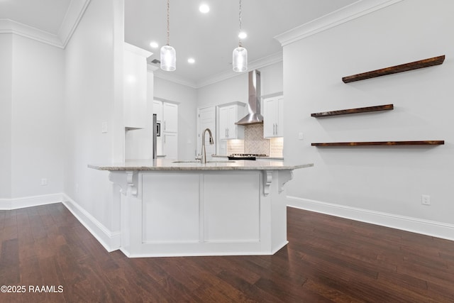 106 Whitewater Dr, Broussard, LA 70518 - kitchen with wall chimney range hood, a peninsula, light stone counters, crown molding, and dark wood-type flooring
