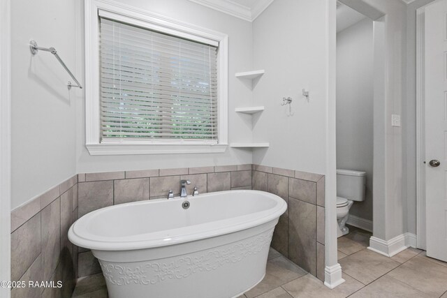 106 Whitewater Dr, Broussard, LA 70518 - bathroom featuring a freestanding tub, tile walls, crown molding, tile patterned flooring, and a wainscoted wall
