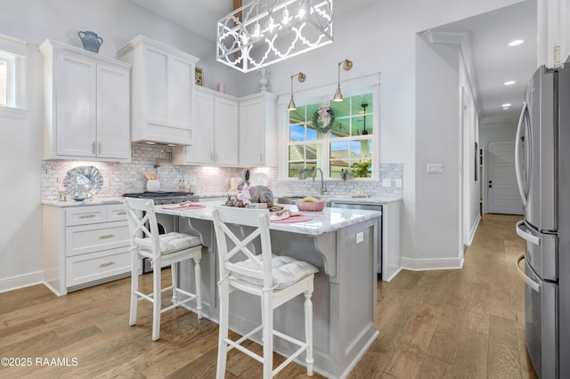 403 Catalina Ln, Youngsville, LA 70592 - kitchen with freestanding refrigerator, white cabinetry, light wood-style floors, and backsplash