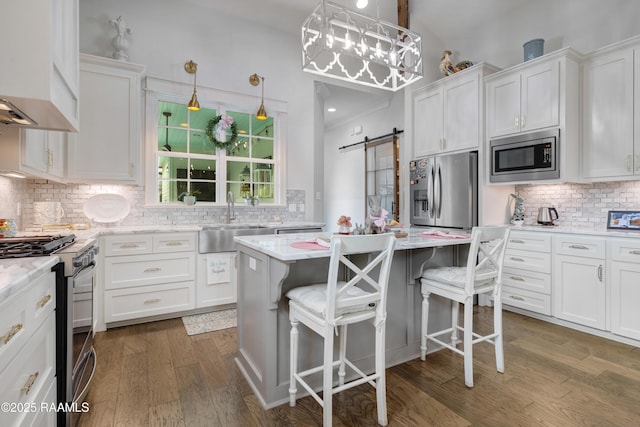 403 Catalina Ln, Youngsville, LA 70592 - kitchen with appliances with stainless steel finishes, tasteful backsplash, white cabinets, wood finished floors, and a barn door