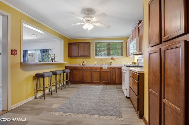 101 Sherry St, Baldwin, LA 70514 - kitchen featuring white appliances, a kitchen bar, ceiling fan, light wood-style flooring, and ornamental molding