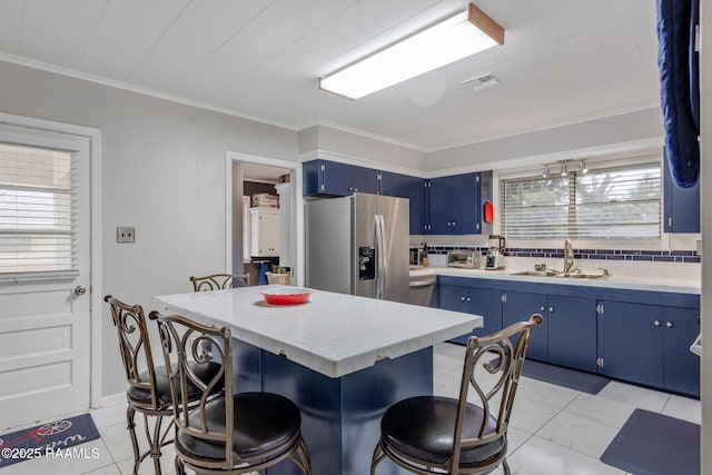 522 Caroline St, New Iberia, LA 70560 - kitchen featuring blue cabinetry, stainless steel fridge with ice dispenser, light countertops, a breakfast bar area, and ornamental molding