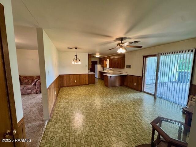 110 W Tampico St, New Iberia, LA 70563 - kitchen with a peninsula, a wainscoted wall, light countertops, brown cabinetry, and wooden walls
