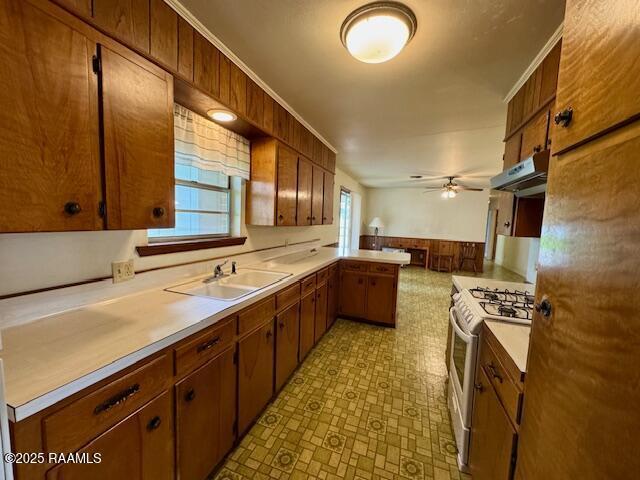 110 W Tampico St, New Iberia, LA 70563 - kitchen featuring white gas range, under cabinet range hood, a peninsula, a ceiling fan, and light countertops