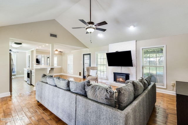 13723 Lynnedale Loop, Abbeville, LA 70510 - living area with a ceiling fan, light wood-style floors, a brick fireplace, and high vaulted ceiling