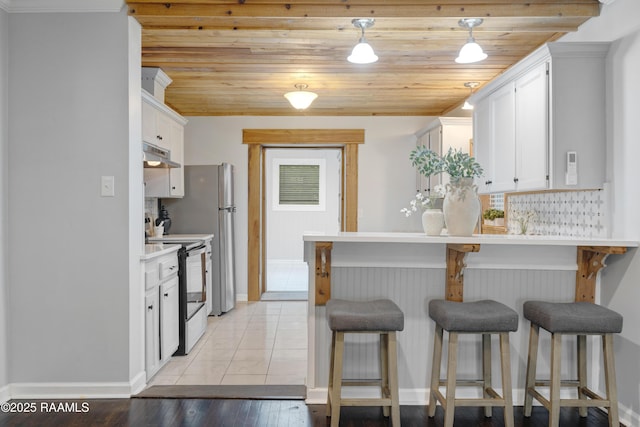 610 Ashton St, New Iberia, LA 70563 - kitchen with electric range, under cabinet range hood, a kitchen bar, white cabinets, and wood ceiling