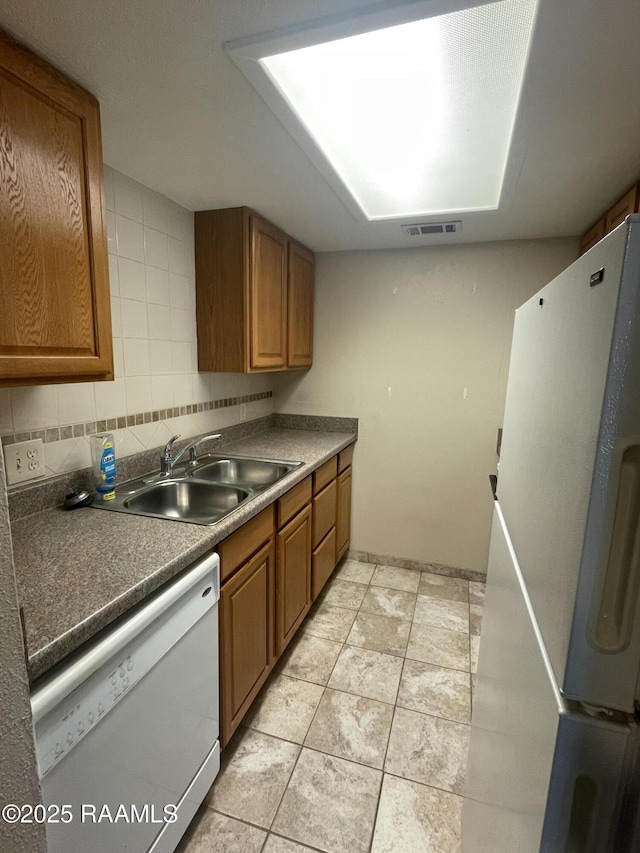 3121 Johnston St Apt 139, Lafayette, LA 70503 - kitchen with white appliances, brown cabinets, dark countertops, and decorative backsplash