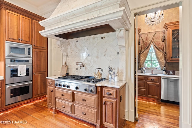 232 Princeton Woods Loop, Lafayette, LA 70508 - kitchen featuring stainless steel appliances, premium range hood, light wood-style flooring, tasteful backsplash, and ornamental molding