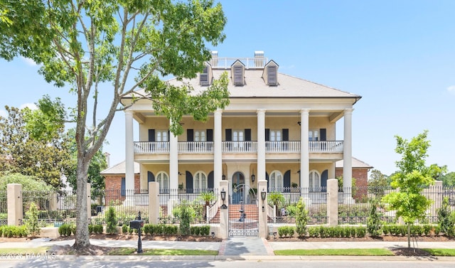 232 Princeton Woods Loop, Lafayette, LA 70508 - neoclassical / greek revival house featuring a balcony, covered porch, a fenced front yard, stucco siding, and a chimney