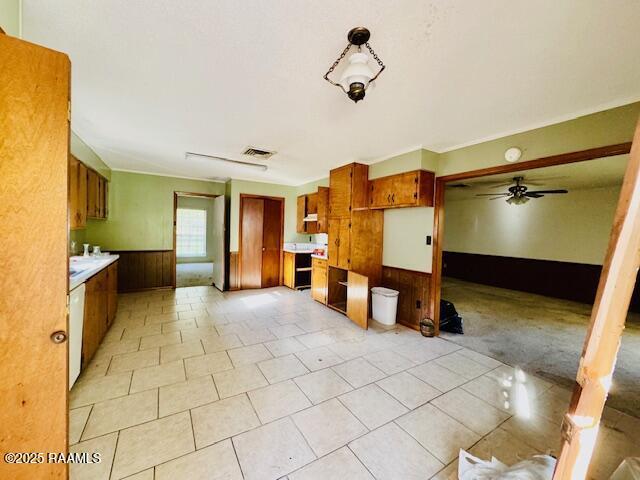 122 Progress Rd, Ville Platte, LA 70586 - kitchen featuring wainscoting, brown cabinets, wood walls, a ceiling fan, and light countertops