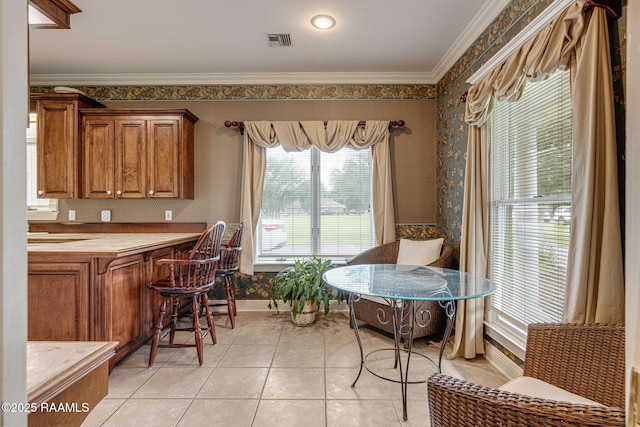 104 Briarfield Dr, Carencro, LA 70520 - kitchen featuring wallpapered walls, brown cabinets, light tile patterned floors, crown molding, and light countertops