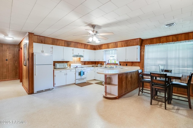 107 Julenie Way, Youngsville, LA 70592 - kitchen featuring white appliances, light countertops, wooden walls, ceiling fan, and a peninsula