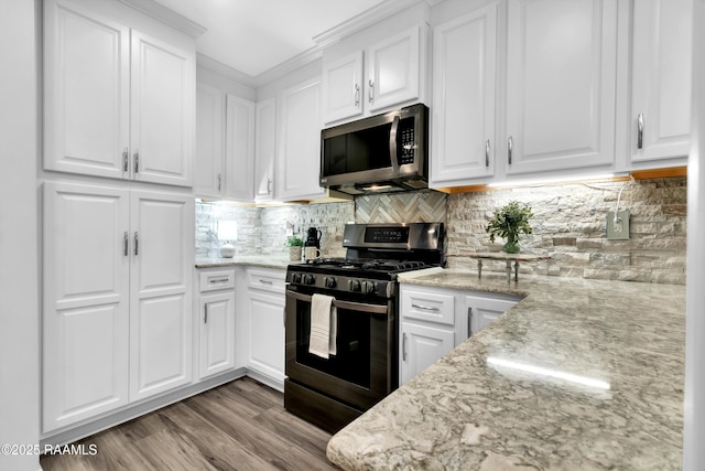 177 Radcliffe Dr, Lafayette, LA 70501 - kitchen featuring stainless steel appliances, white cabinets, light stone counters, light wood-type flooring, and tasteful backsplash