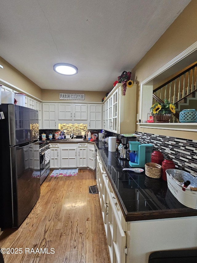 118 Pollard Ave, New Iberia, LA 70563 - kitchen featuring freestanding refrigerator, stainless steel stove, light wood-style floors, dark countertops, and tasteful backsplash