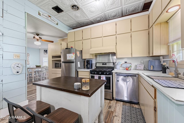 1054 Main St, Parks, LA 70582 - kitchen with appliances with stainless steel finishes, ventilation hood, light wood-type flooring, cream cabinets, and a ceiling fan