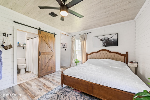 1054 Main St, Parks, LA 70582 - bedroom with wood finished floors, wood ceiling, a barn door, wooden walls, and connected bathroom