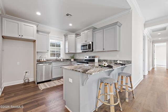 119 Alpine Dr, Lafayette, LA 70506 - kitchen with stainless steel appliances, a peninsula, light stone countertops, wood finished floors, and recessed lighting