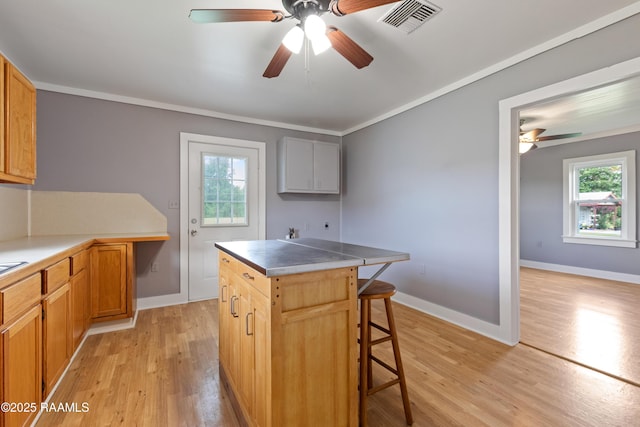 1044 Babineaux Rd, Breaux Bridge, LA 70517 - kitchen with light wood finished floors, ceiling fan, a breakfast bar area, a center island, and ornamental molding