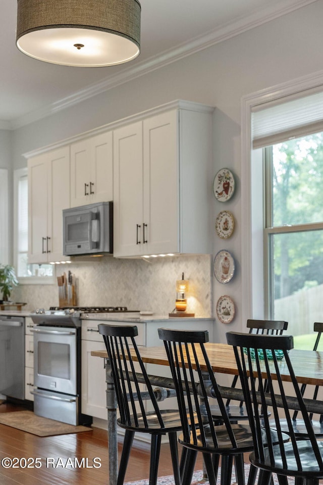 124 Buttercup Dr, Washington, LA 70589 - kitchen featuring stainless steel appliances, crown molding, wood finished floors, tasteful backsplash, and white cabinets