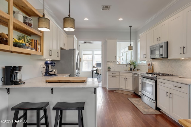 124 Buttercup Dr, Washington, LA 70589 - kitchen featuring appliances with stainless steel finishes, white cabinets, a peninsula, a breakfast bar, and crown molding
