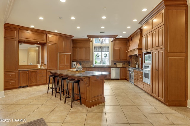 2 Carmel Bnd, New Iberia, LA 70563 - kitchen featuring premium range hood, appliances with stainless steel finishes, brown cabinetry, a center island, and a kitchen bar