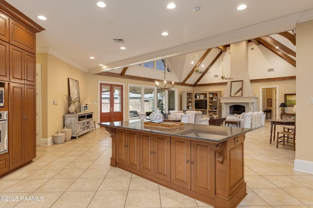 2 Carmel Bnd, New Iberia, LA 70563 - kitchen featuring a kitchen island, light tile patterned flooring, dark stone counters, brown cabinets, and a fireplace