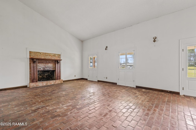 1243 Huval Rd, Breaux Bridge, LA 70517 - unfurnished living room featuring brick flooring, plenty of natural light, high vaulted ceiling, and a fireplace