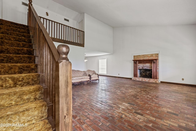 1243 Huval Rd, Breaux Bridge, LA 70517 - unfurnished living room featuring high vaulted ceiling, brick floors, stairs, and a brick fireplace