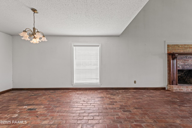 1243 Huval Rd, Breaux Bridge, LA 70517 - spare room featuring a textured ceiling, a chandelier, a fireplace, and brick flooring