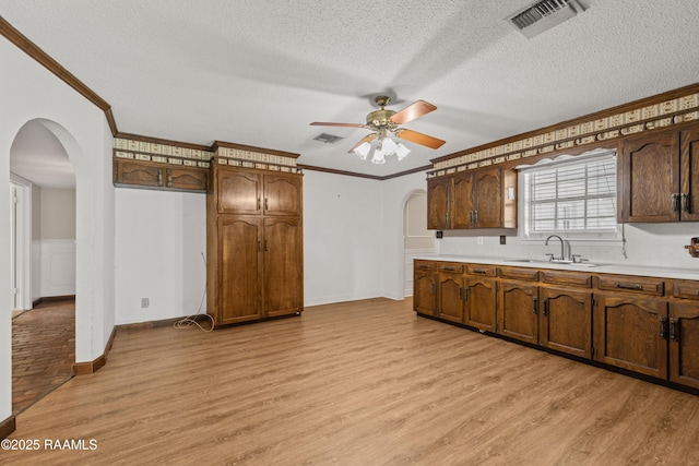 1243 Huval Rd, Breaux Bridge, LA 70517 - kitchen featuring arched walkways, ceiling fan, light wood-type flooring, crown molding, and light countertops