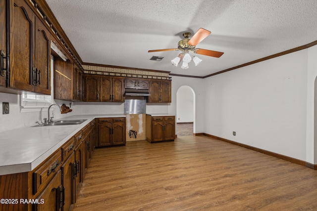 1243 Huval Rd, Breaux Bridge, LA 70517 - kitchen with arched walkways, light wood-style floors, a ceiling fan, crown molding, and a textured ceiling