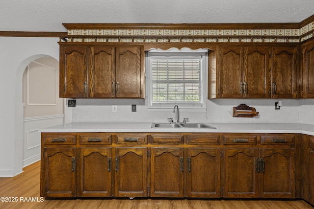 1243 Huval Rd, Breaux Bridge, LA 70517 - kitchen with a textured ceiling, light countertops, arched walkways, light wood finished floors, and crown molding