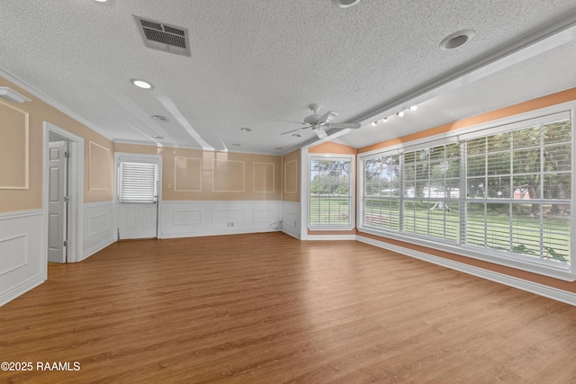 1243 Huval Rd, Breaux Bridge, LA 70517 - unfurnished living room featuring a textured ceiling, wood finished floors, ceiling fan, a decorative wall, and a wainscoted wall