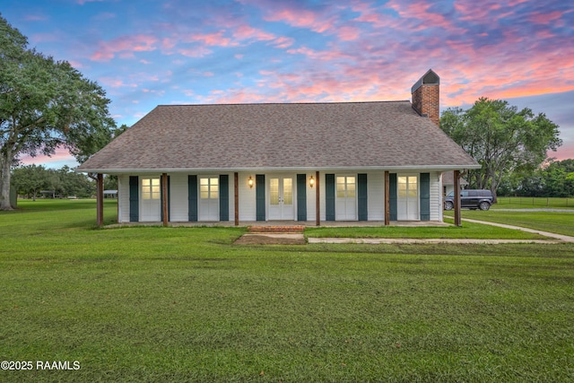 1243 Huval Rd, Breaux Bridge, LA 70517 - view of front of property featuring a yard, a chimney, a shingled roof, french doors, and covered porch