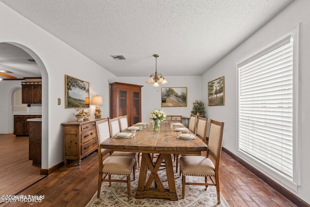 1243 Huval Rd, Breaux Bridge, LA 70517 - dining room featuring arched walkways, a textured ceiling, a chandelier, and dark wood-style floors