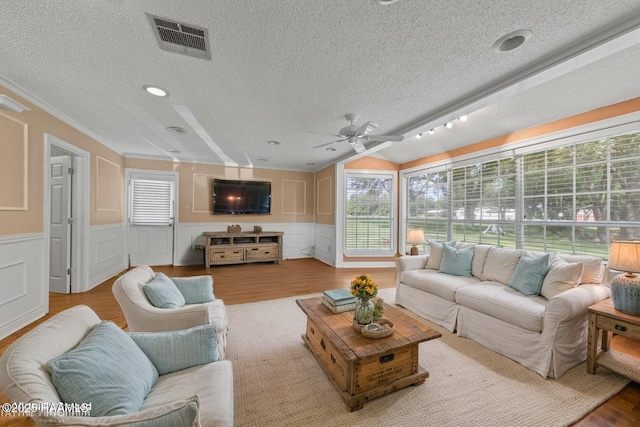 1243 Huval Rd, Breaux Bridge, LA 70517 - living room with a textured ceiling, wood finished floors, a ceiling fan, a decorative wall, and crown molding