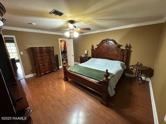 2033 Isadore Rd, Erath, LA 70533 - bedroom featuring wood finished floors, crown molding, ceiling fan, a walk in closet, and a closet