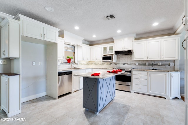 314 Creswell Ave, Scott, LA 70583 - kitchen featuring appliances with stainless steel finishes, white cabinets, decorative backsplash, ornamental molding, and under cabinet range hood